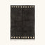 Full view of the Amanar charcoal Beni Ourain rug with a bold border block motif and hand-tied fringe.