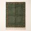 Sage and terracotta Mrirt rug with square dot border, flat lay on plain background