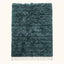 Full view of teal Beni Ourain rug with diamond lattice pattern and cream fringe on plain background