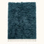 Flat lay of teal Beni Ourain rug with textured pile and ivory fringe