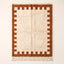 Terracotta and ivory Beni Ourain rug with crenellated battlement border on plain background, flat lay