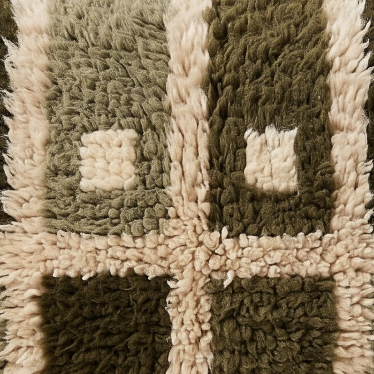 Close-up of the center cross on the Afrag Moroccan wool pillow showing olive and sage pile