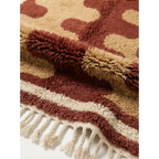 Folded edge detail of the Aderfi rug showing terracotta, camel and ivory hand-knotted wool.