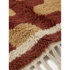 Fringe corner of the Aderfi terracotta and camel Beni Ourain rug with ivory border.