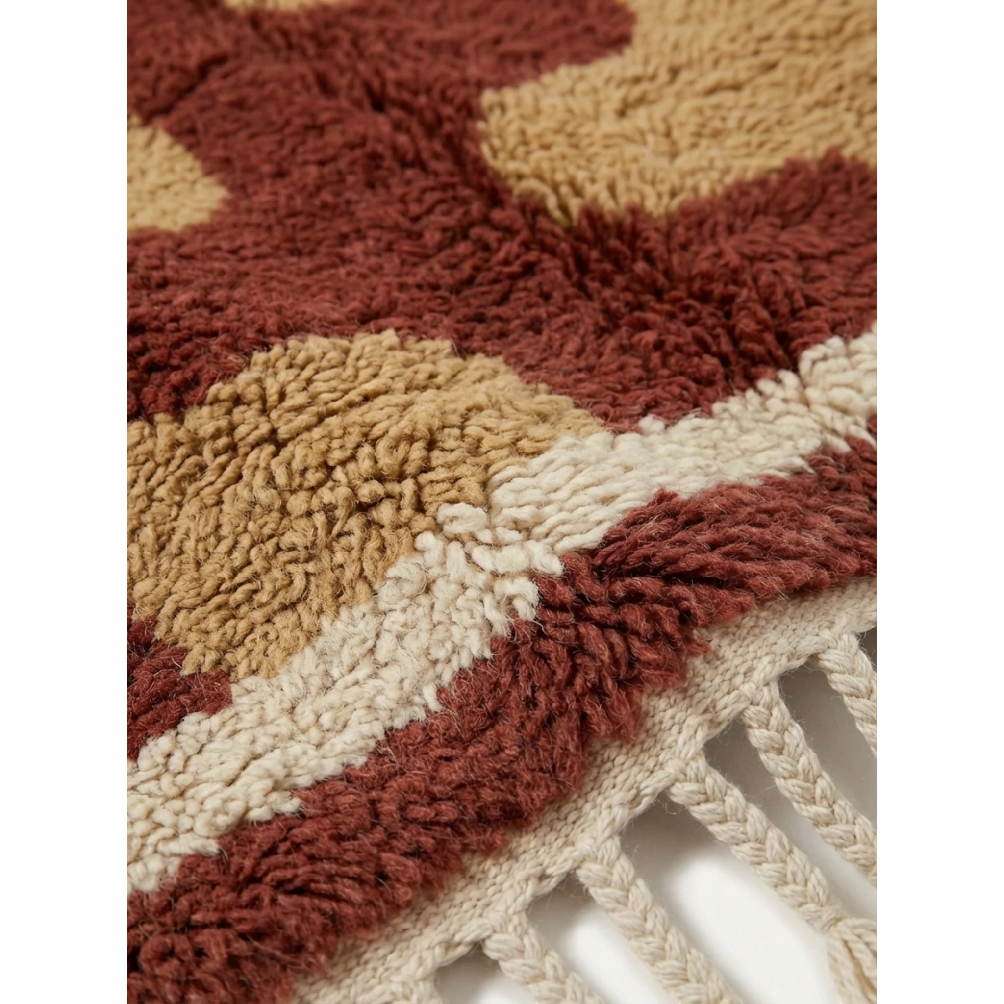 Fringe corner of the Aderfi terracotta and camel Beni Ourain rug with ivory border.