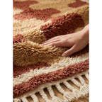 Hand pressing the soft high-pile wool of the Aderfi terracotta and camel Beni Ourain rug.