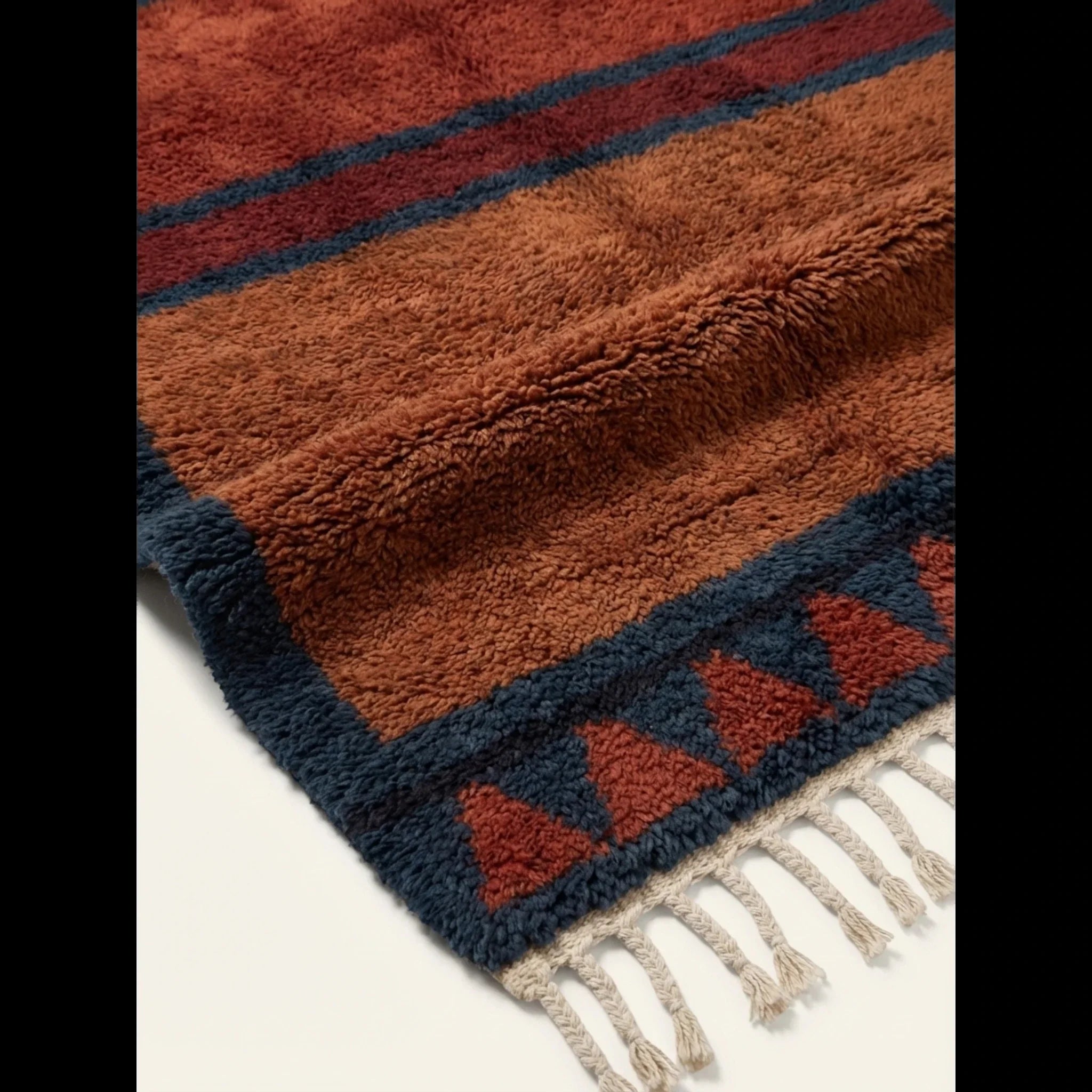 Hand-tied fringe and plush Atlas wool detail of the Aksel rust and navy rug.