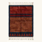 Full view of the Aksel rust Beni Ourain rug with a navy framed triangle motif and hand-tied fringe.
