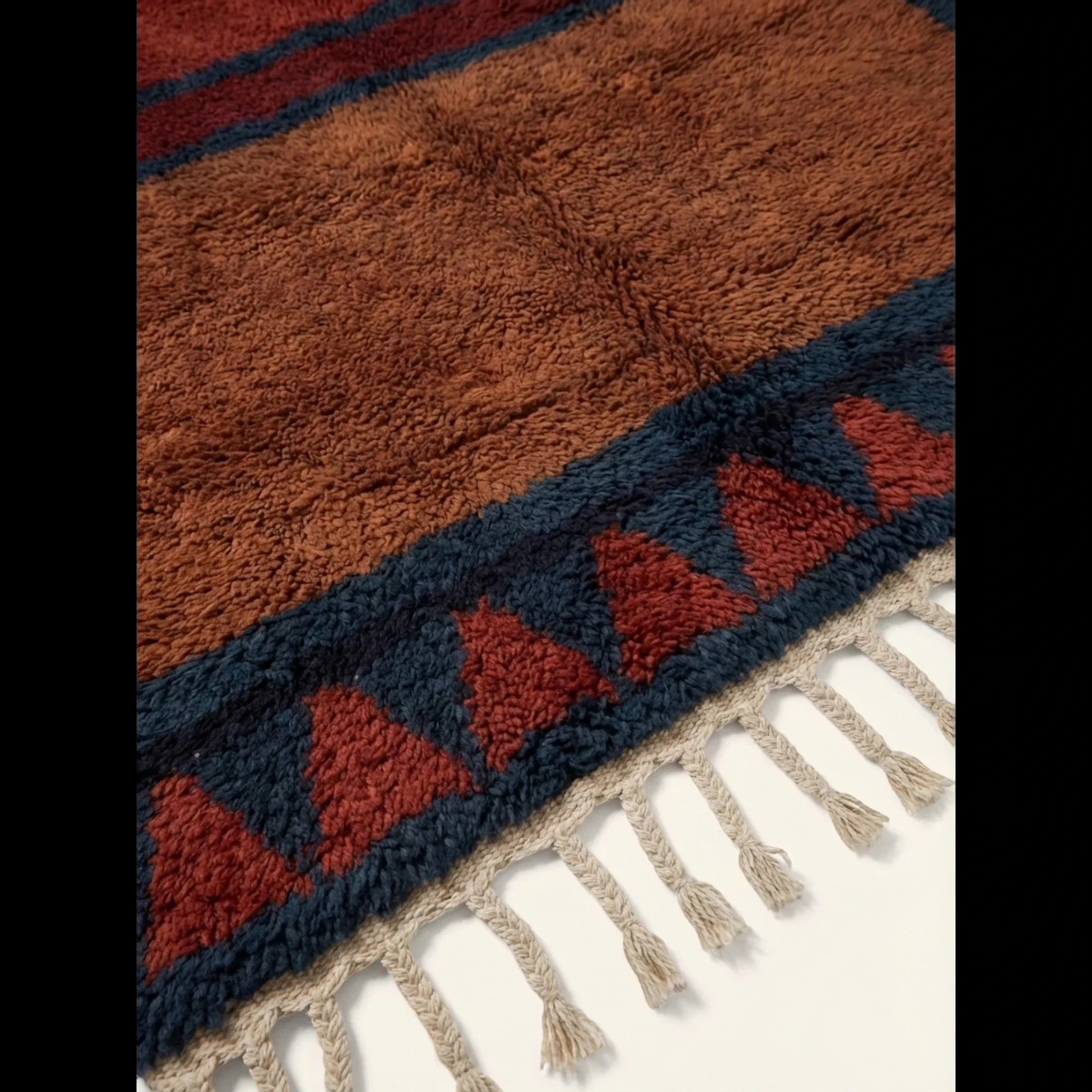 Close-up of the rust and navy framed triangle motif on the Aksel rug.