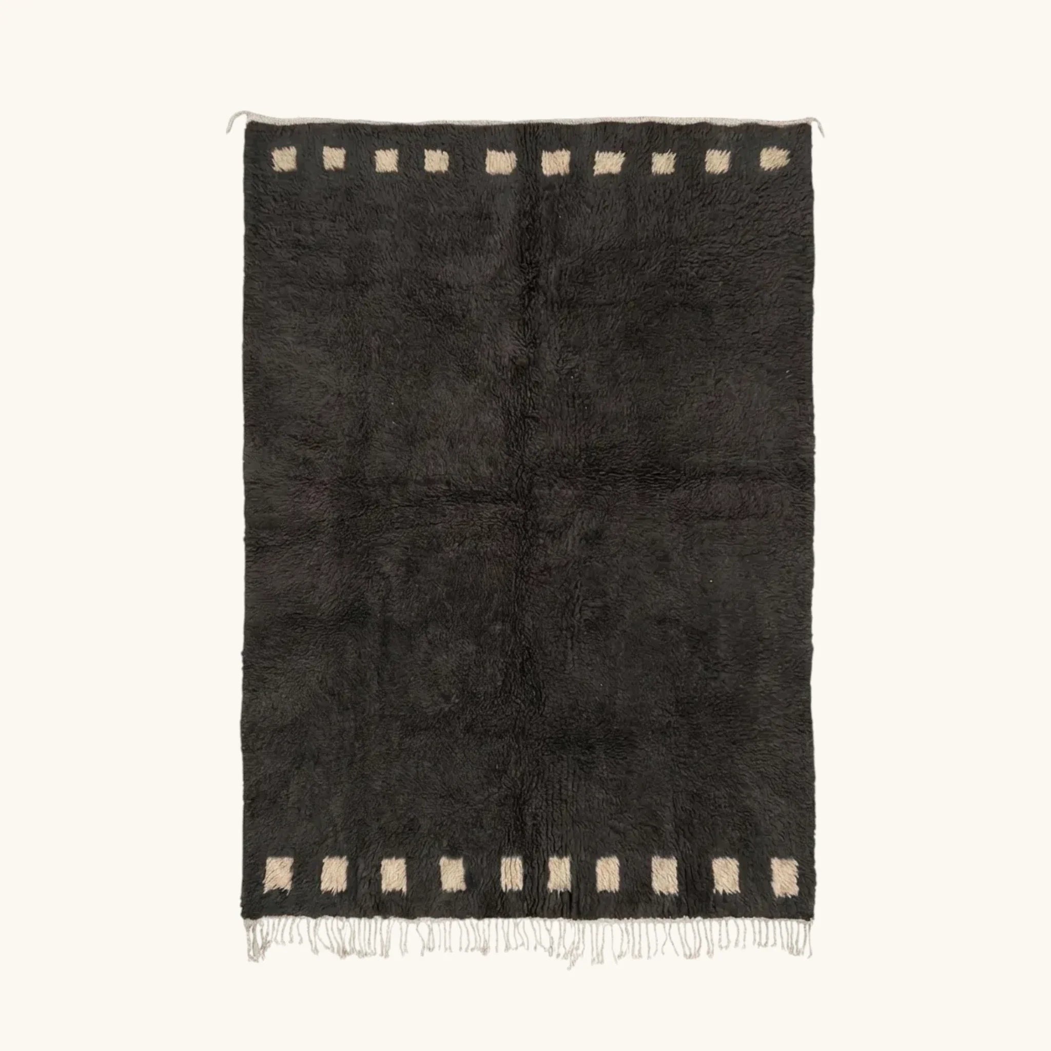 Full view of the Amanar charcoal Beni Ourain rug with a bold border block motif and hand-tied fringe.
