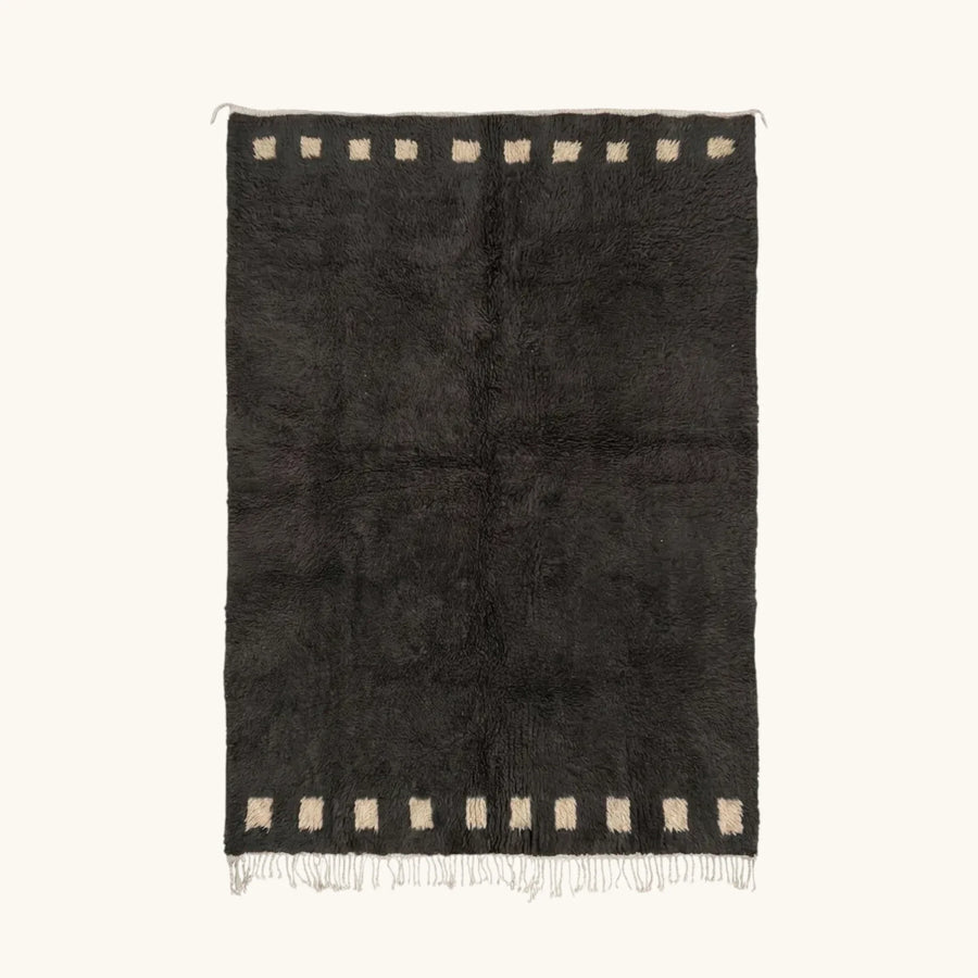 Full view of the Amanar charcoal Beni Ourain rug with a bold border block motif and hand-tied fringe.