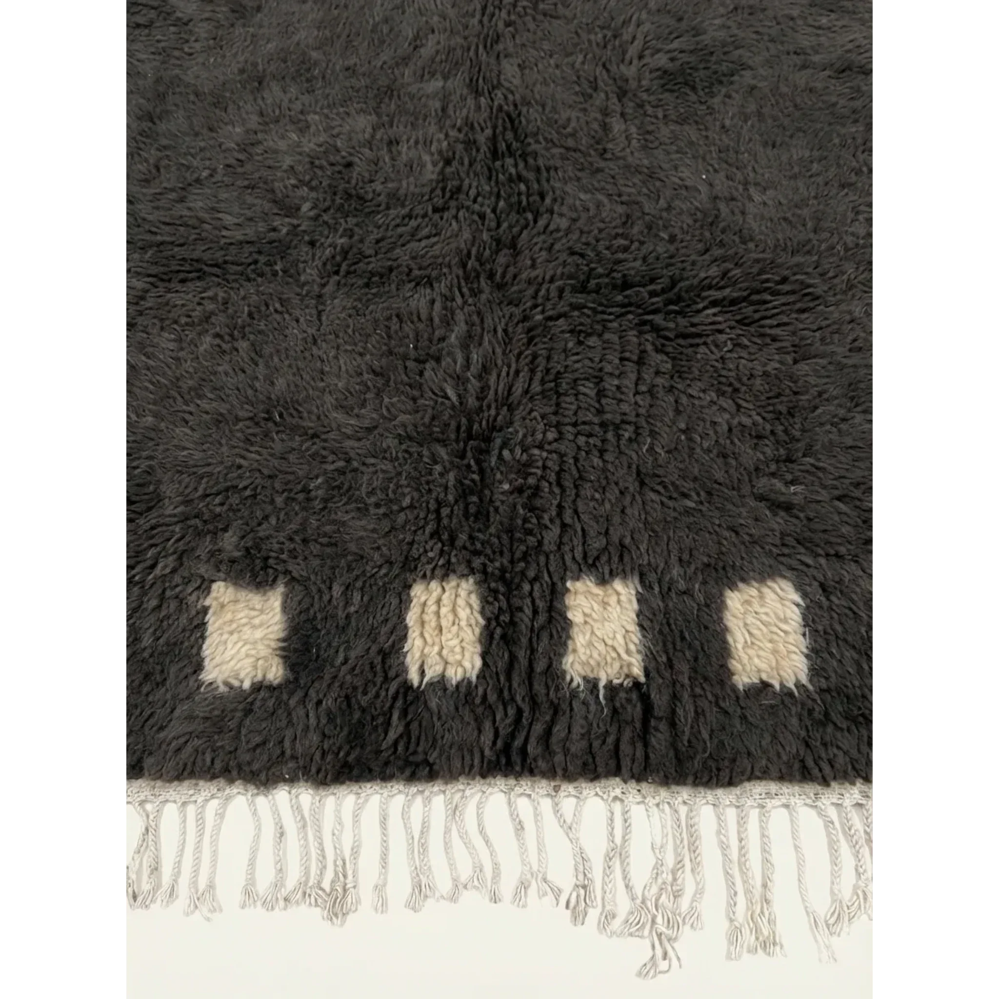 Detailed view of the charcoal and ivory border block pattern on the Amanar rug.