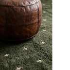 Amnay green Beni Ourain rug styled beside a sculptural leather chair.