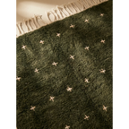 Close-up of the deep green Atlas wool texture and ivory motifs on the Amnay rug.