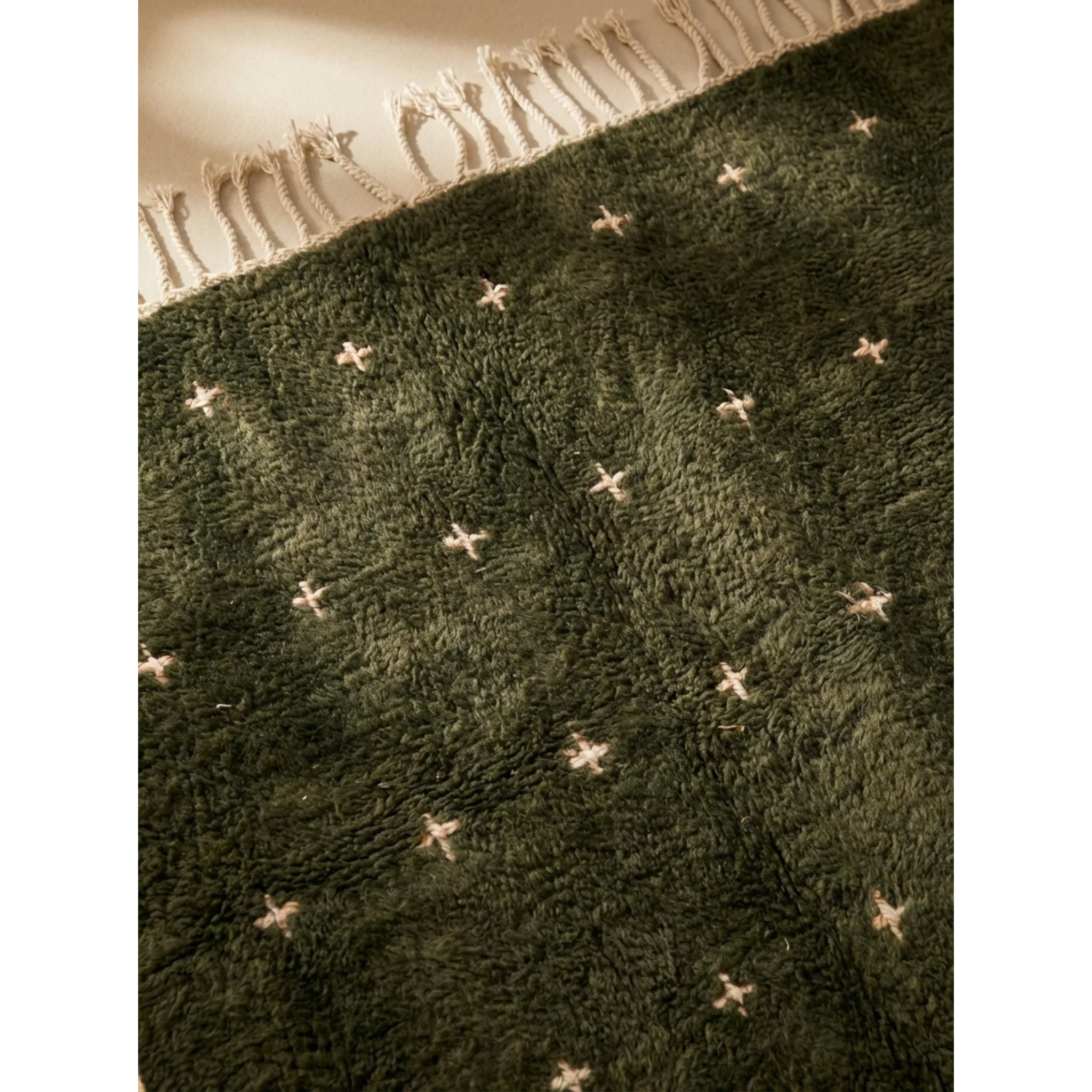 Close-up of the deep green Atlas wool texture and ivory motifs on the Amnay rug.