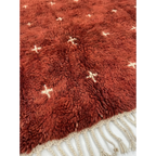 Detailed view of the small ivory cross pattern across the Azru terracotta rug.