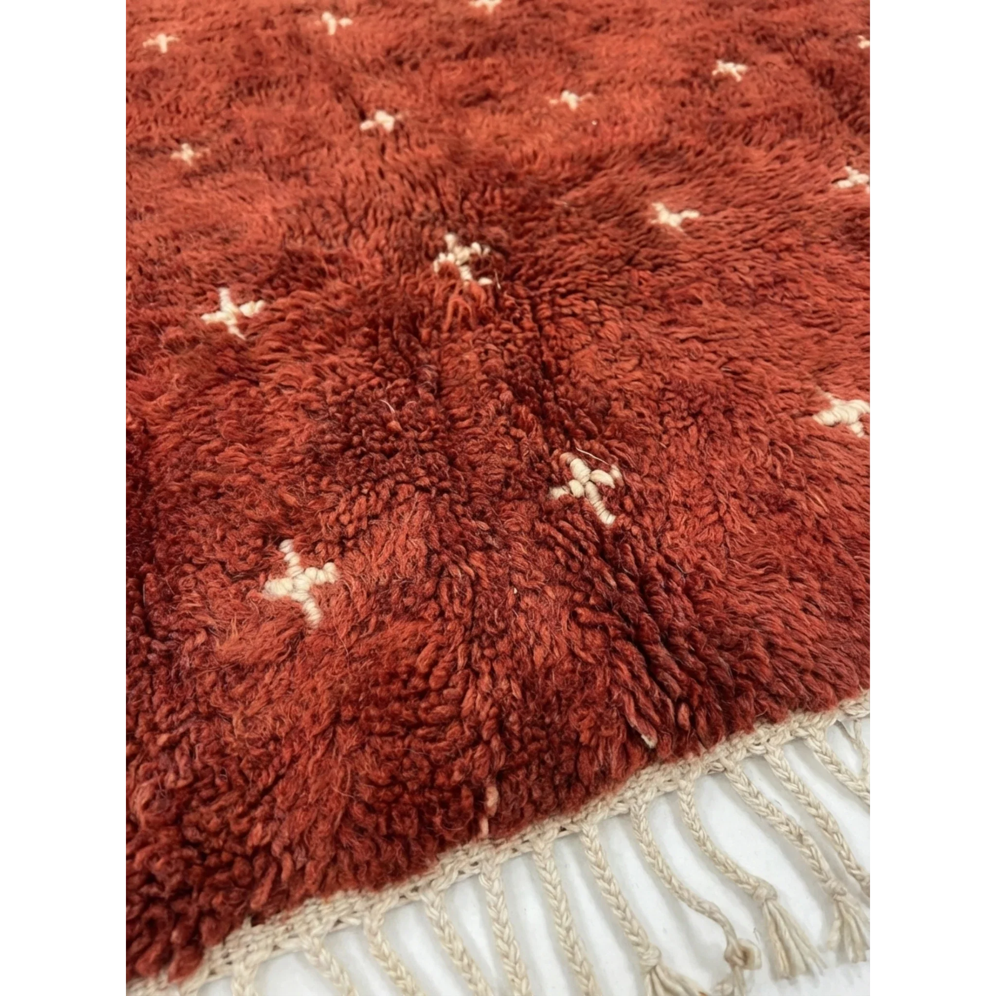 Detailed view of the small ivory cross pattern across the Azru terracotta rug.