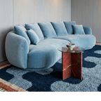 Azul navy blue Beni Ourain rug styled beneath a curved blue sofa in a contemporary living room.