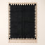 Black and ivory Beni Ourain rug with sawtooth triangle border, flat lay on plain background