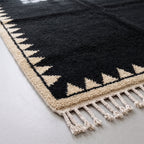 Corner detail showing sawtooth triangle motif and cream wool fringe on black Beni Ourain rug
