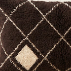 Side view of the Ayur Moroccan pillow showing its black and ivory wool pile