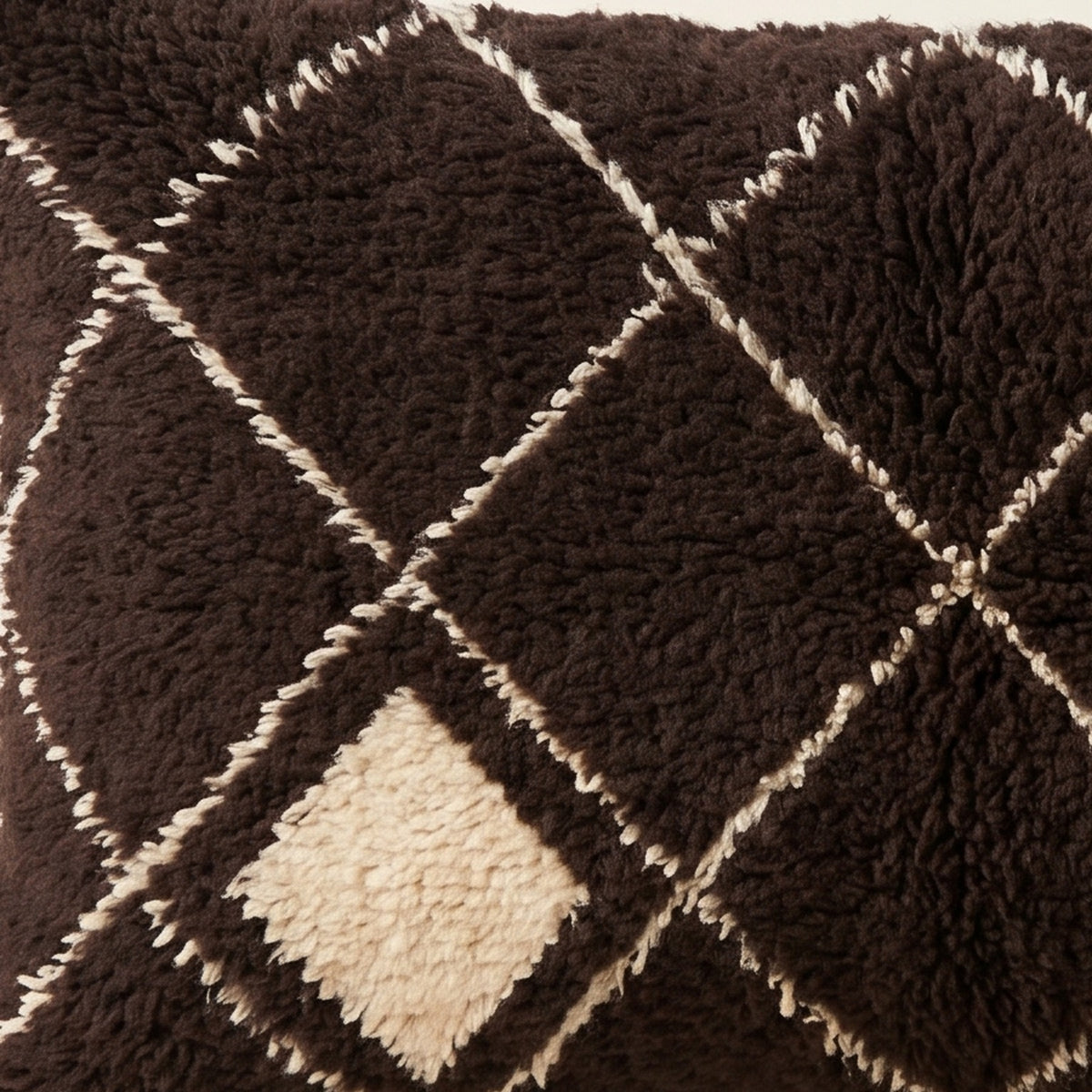 Side view of the Ayur Moroccan pillow showing its black and ivory wool pile