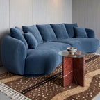 Fawn Beni Ourain rug layered under modern blue curved sofa with side table in living room