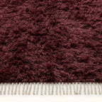 Detailed view of burgundy Beni Ourain pile with natural wool texture and fringe