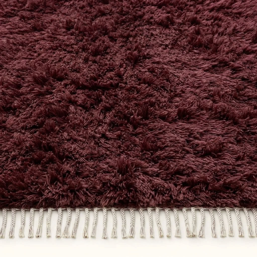 Detailed view of burgundy Beni Ourain pile with natural wool texture and fringe