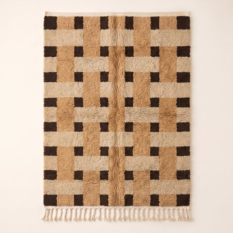 Camel, cream and cocoa brown Beni Ourain rug with checkerboard block pattern, flat lay on plain background