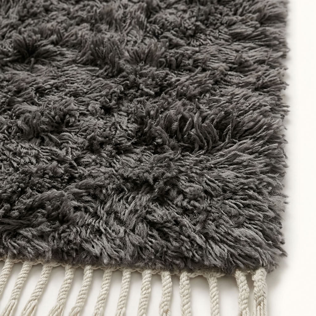 Close-up of charcoal Beni Ourain pile texture showing soft wool knots and ivory fringe edge