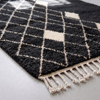 Detail of the fringe edge and underside of the charcoal and ivory Beni Ourain rug showing the dense knotted construction