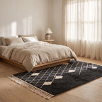 Charcoal and ivory Beni Ourain rug placed at the foot of a bed in a minimalist bedroom with natural light