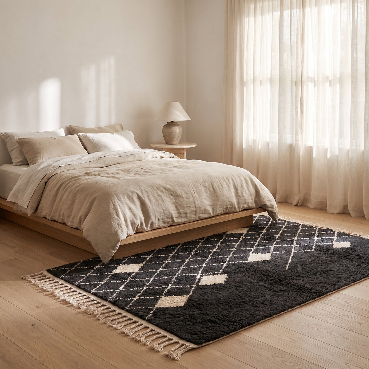 Charcoal and ivory Beni Ourain rug placed at the foot of a bed in a minimalist bedroom with natural light