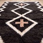 Detail of central diamond and terracotta cross motif on charcoal ground with ivory outline