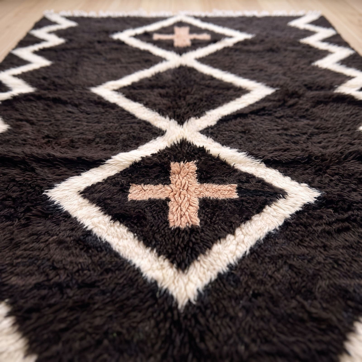 Detail of central diamond and terracotta cross motif on charcoal ground with ivory outline