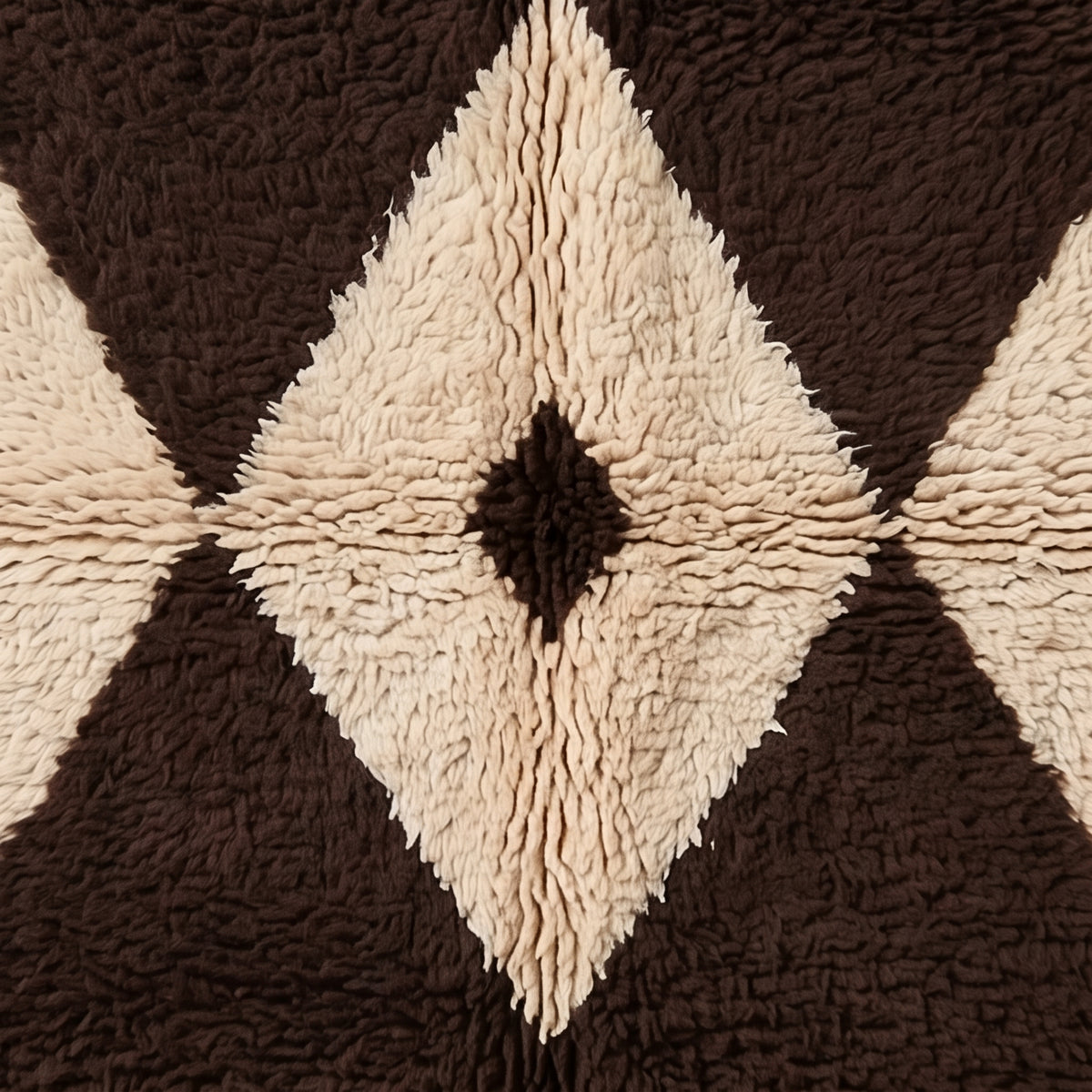 Detailed view of Massa's central diamond motif with brown outer frame, ivory inner diamond, and small black eye, showing wool knotwork