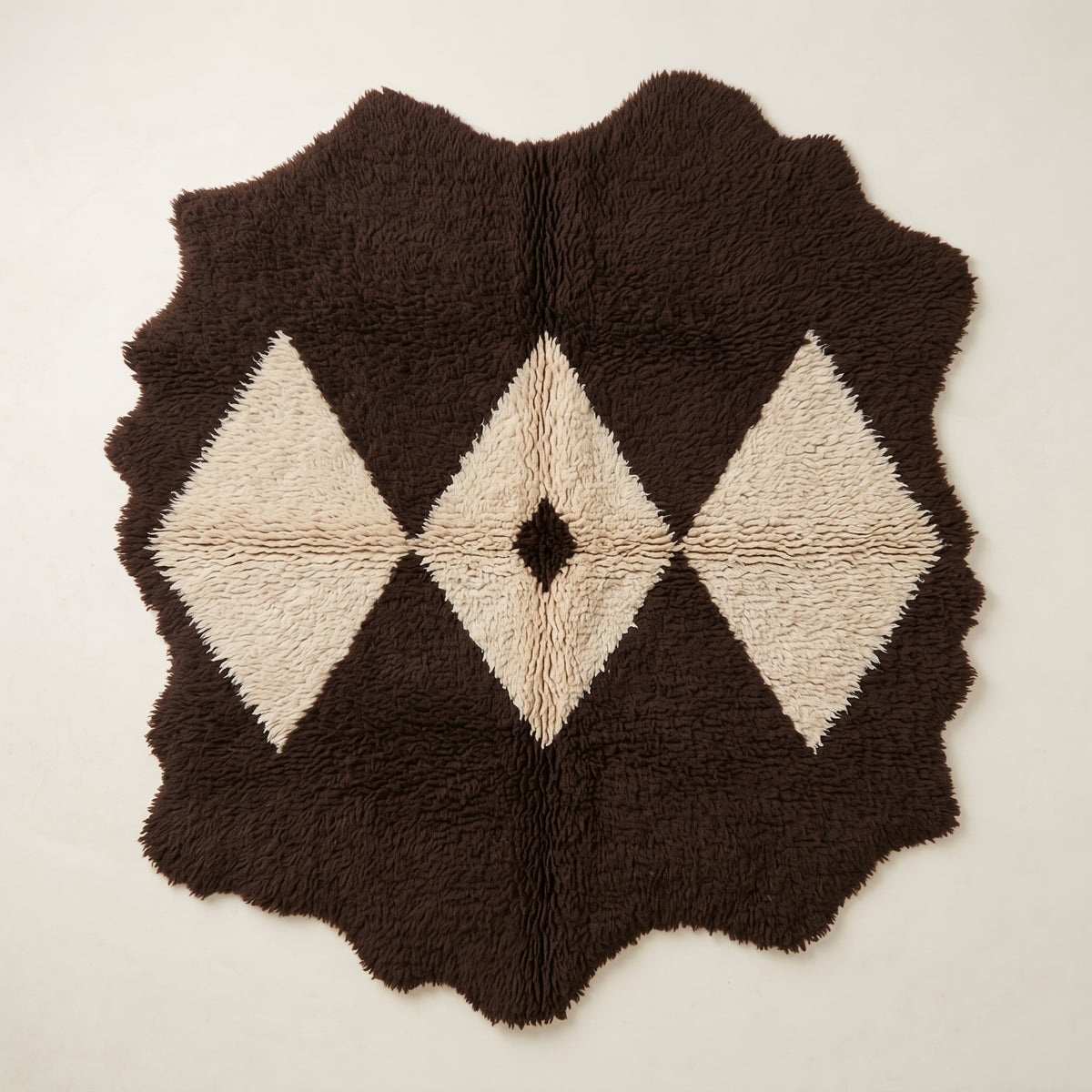 Flat view of Massa, a chocolate brown and ivory Beni Ourain rug with a diamond lattice motif and dark centre eye, irregular wavy edges, thick soft pile