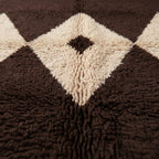 Close-up of Massa's diamond lattice motif showing thick hand-knotted wool pile in chocolate brown and ivory with black centre eye detail