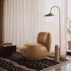 Chocolate and taupe Beni Ourain rug layered in a modern living room with tan leather chair and brass arc lamp