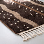 Side angle detail of soft wool pile with cream motifs and cream fringe edge