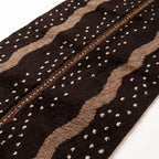 Close-up of hand-knotted pile showing scattered cream dots on chocolate field with taupe vertical columns