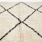 Close-up of a cream-colored shag rug with a black diamond pattern.