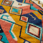 Pattern close-up of Izuran showing coral, mustard, teal and navy outlined diamonds and angular lines
