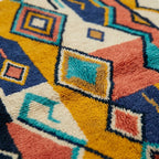 Fringe and lower-edge detail of Izuran with coral, mustard, teal and navy geometric motifs