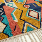 Close-up of the Izuran Boujaad rug showing plush hand-knotted wool around mustard and navy diamond forms