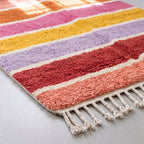 Detail shot of Tamuli rug pile showing individual colour bands with cream separator stripes and soft wool texture