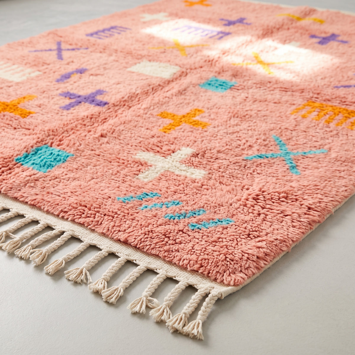 Angled detail shot of wool texture and hand-drawn motifs including yellow X, turquoise dash marks and cream geometric blocks