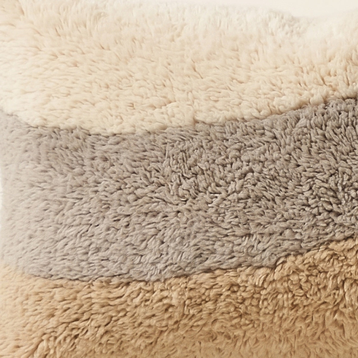 Side view of the Tilelli Moroccan pillow showing its cream, grey and sand wool pile