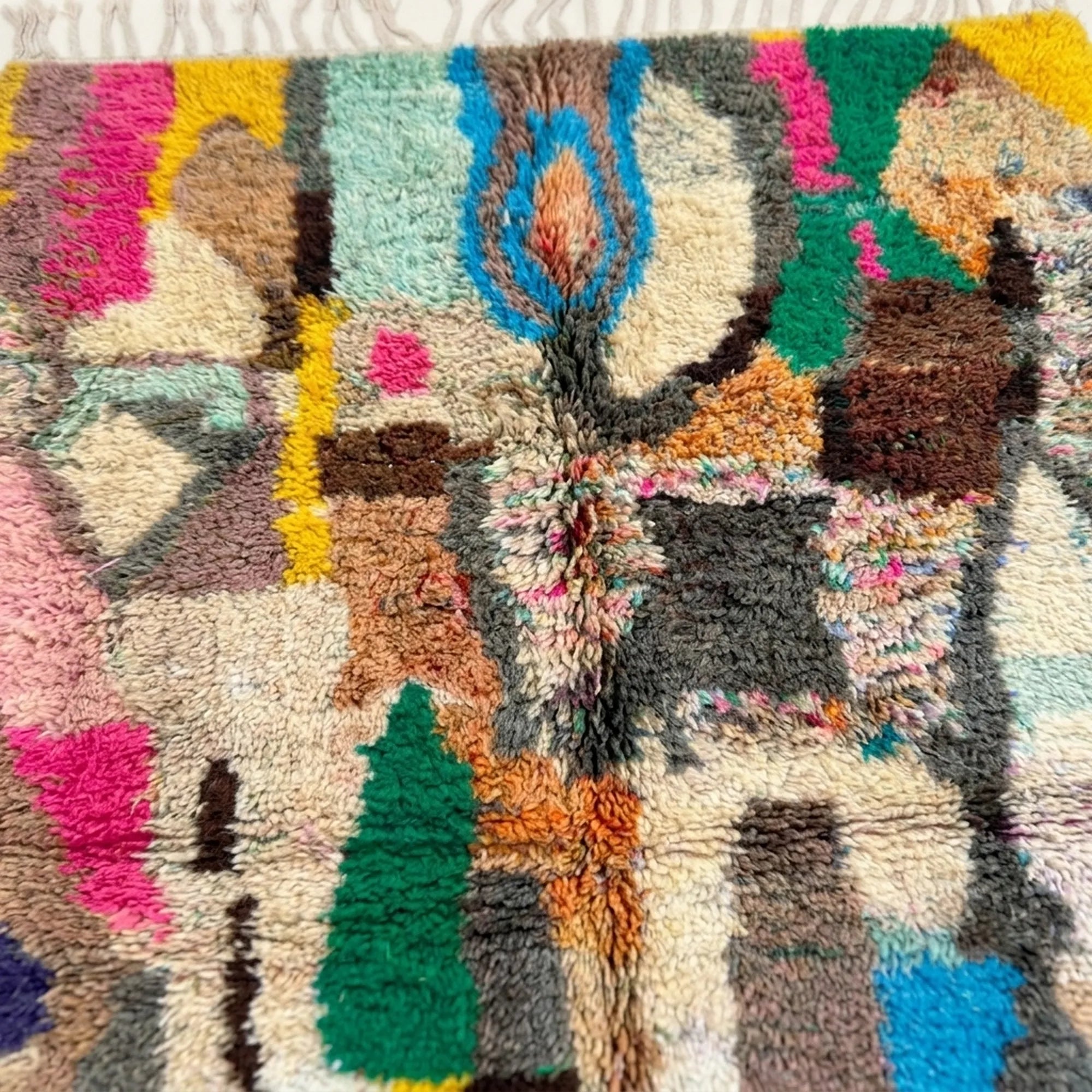 Pattern close-up of Tifran showing pink, green, blue, black and ochre abstract blocks and linear marks on cream wool
